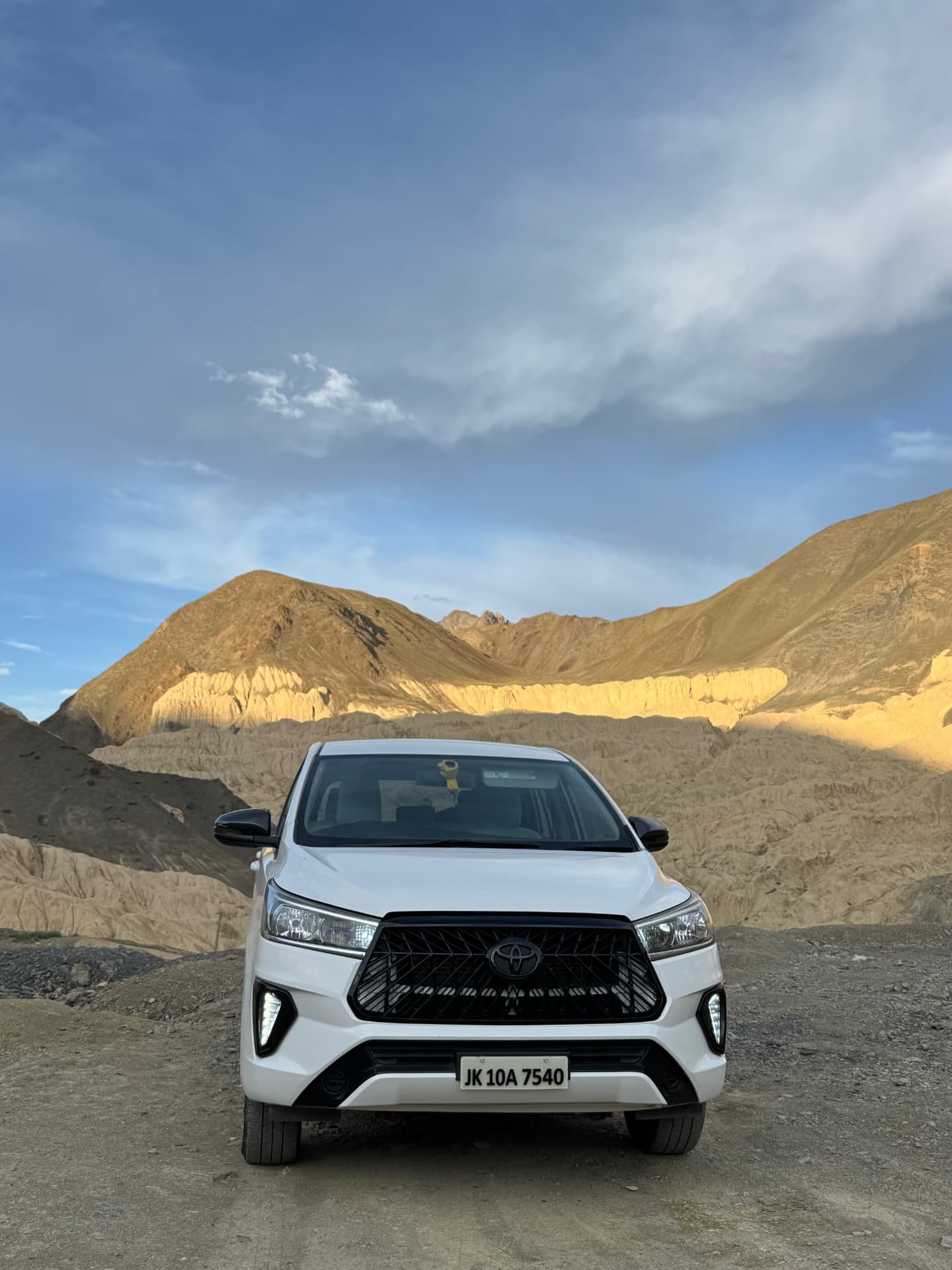White Toyota Innova Crysta parked on a Ladakh mountain pass at sunrise